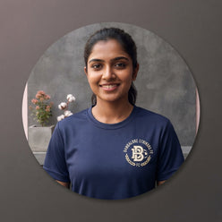 A circular portrait of Kavya Nair wearing a navy blue collegiate graphic t-shirt with a football motif in an urban setting.