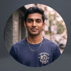 A close-up portrait of Vikram Patel wearing a navy blue collegiate graphic tee, set against a blurred urban Bangalore backgro